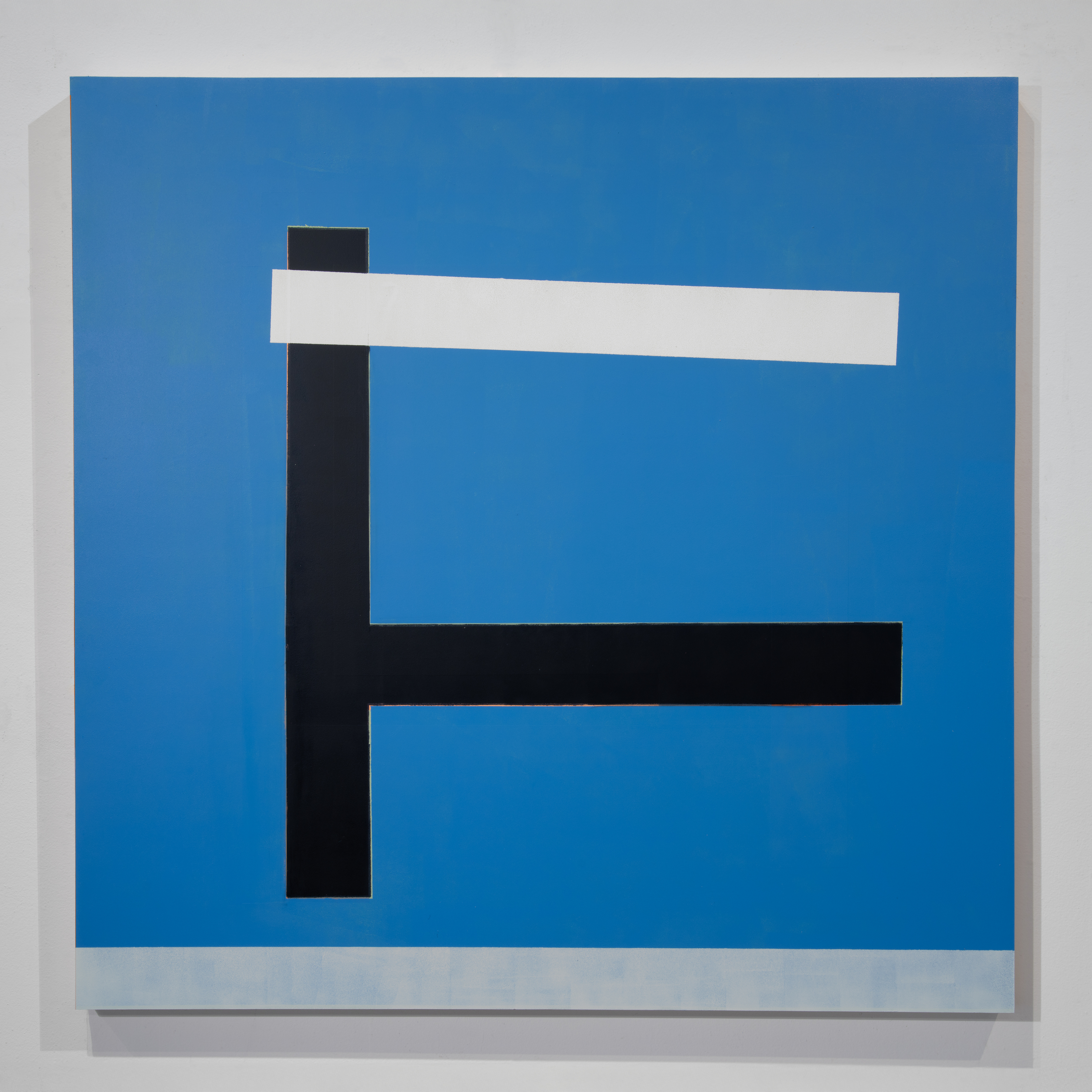 Abstract geometric composition featuring a vertical black rectangle intersected by a horizontal white band against a bright blue background, with a smaller black horizontal element below, on a wooden panel with subtle shadow effects.