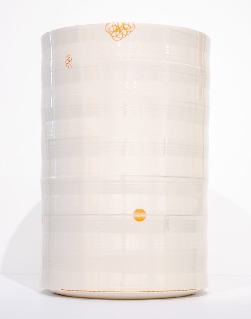 A cream-colored cylindrical porcelain vessel with horizontal ridges and delicate orange line drawings scattered across its surface, including abstract scribbled motifs near the top and a solid circle positioned on the lower section. The vase is photographed against a white background with subtle shadowing.