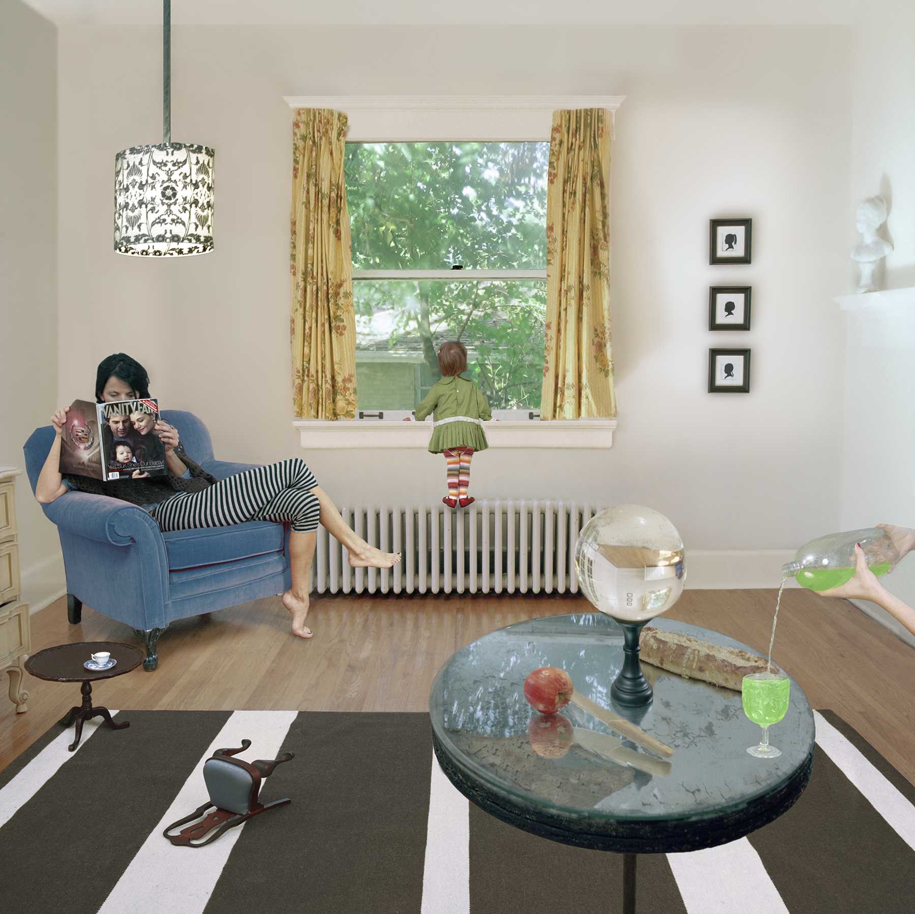 A staged domestic interior scene featuring a woman seated in a blue armchair reading a magazine, while a child in a green dress stands at a large window with golden curtains overlooking green foliage. The foreground contains a black and white striped floor with a round table displaying a crystal ball, an apple, a globe, and a cocktail glass. Cream-colored walls are adorned with a patterned pendant light, silhouette portraits, and a radiator beneath the window. Objects are arranged throughout the space with surreal and whimsical juxtaposition.
