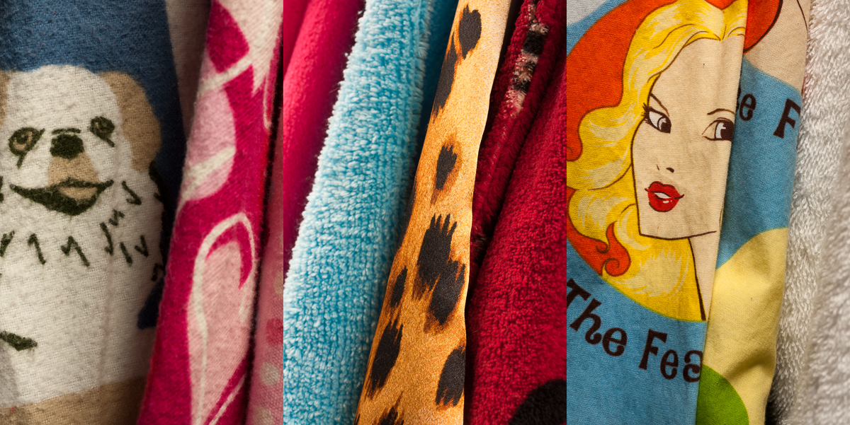 A collection of colorful fabric swatches displayed vertically, featuring playful printed designs including a smiling dog face, hearts, animal spots, and a portrait of a blonde woman with red lips. The textiles showcase vibrant hues of cream, hot pink, turquoise, mustard yellow, and burgundy red.