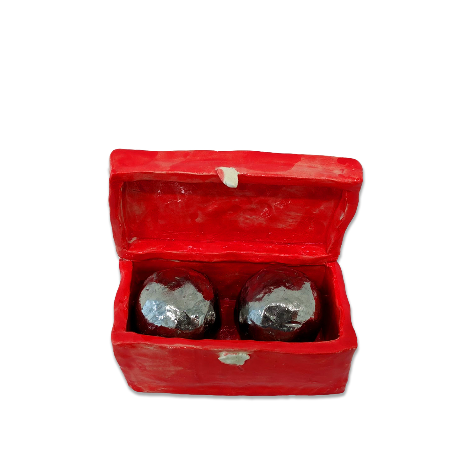 A bright red clay box with hinged lid sits open to reveal two dark spherical objects with silvery metallic surfaces nestled inside.