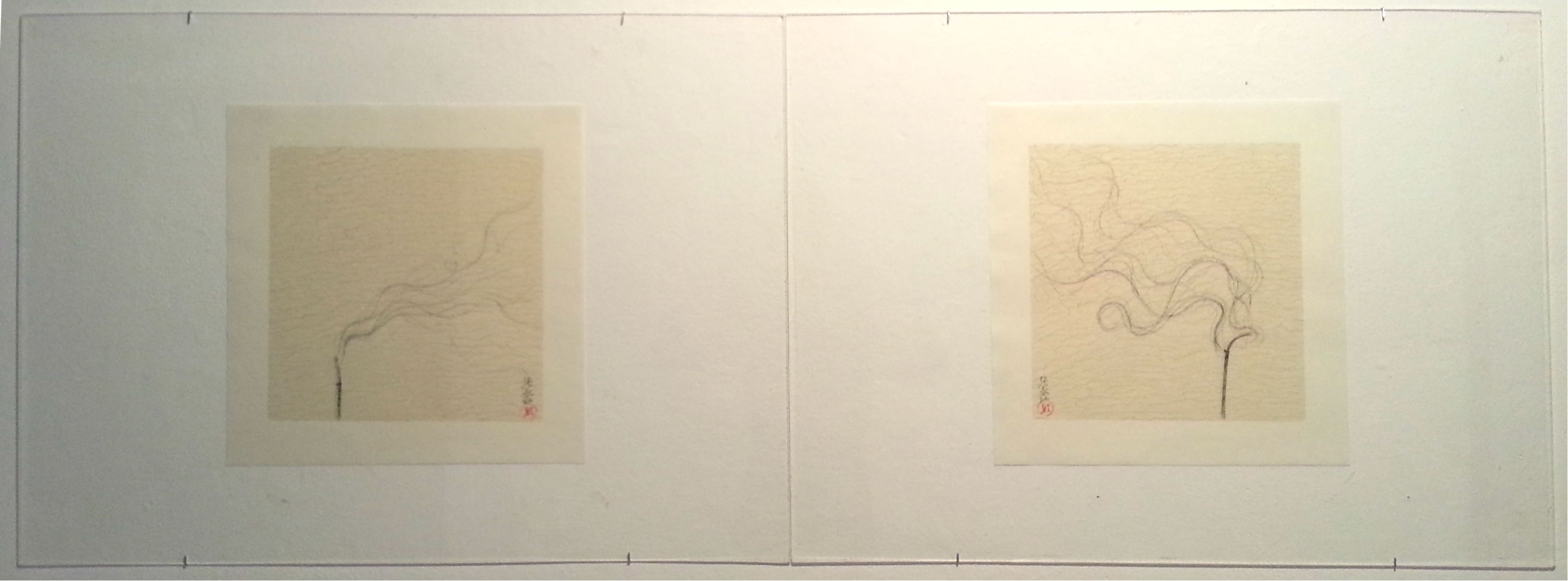 Two delicate ink drawings on cream-colored rice paper mounted on white backing sheets, displayed side by side. Each composition features minimalist brushwork depicting a slender, twisted branch or stem with flowing, organic lines rendered in gray-black ink. Small red seal marks appear in the lower right of each work. The pale, translucent quality of the paper and the restraint of the linework create an understated, meditative aesthetic.