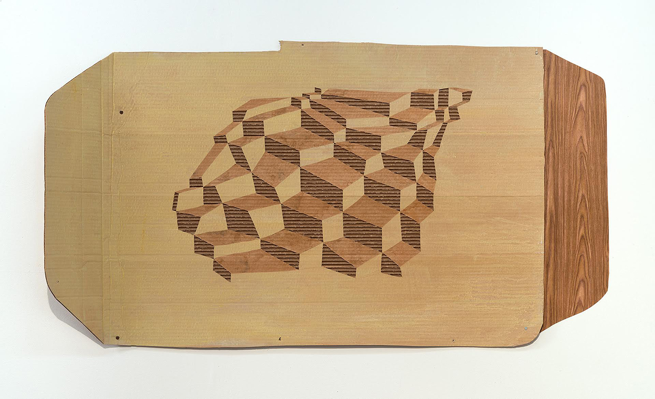 Wooden relief panel featuring an isometric cubic pattern carved in varying depths, creating a three-dimensional optical effect through contrasting light and dark wood tones. The pale rectangular board is mounted against a white background with visible fasteners along its edges.