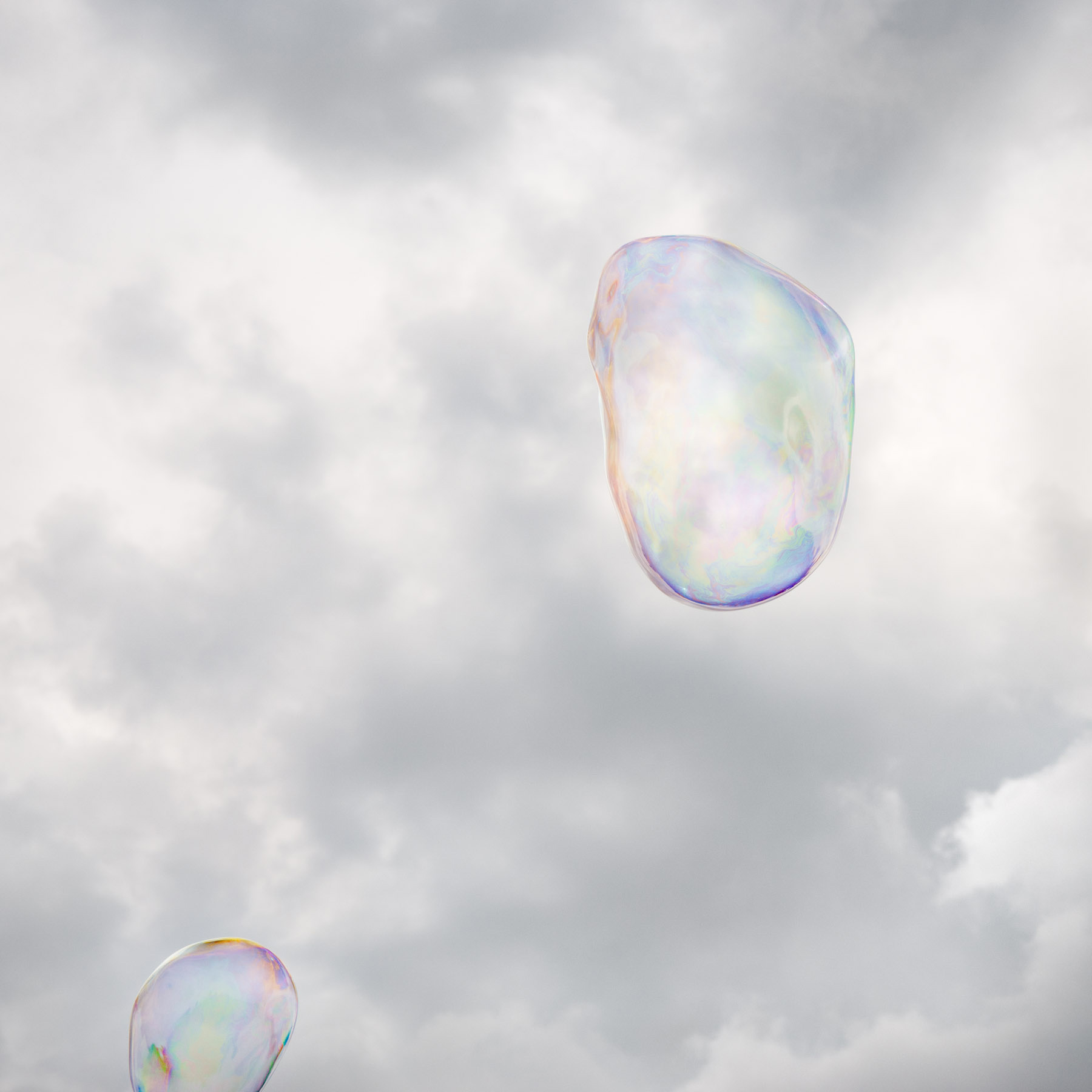 Two iridescent soap bubbles floating against a cloudy gray sky, their translucent surfaces reflecting soft pastel hues of blue, pink, yellow, and green.