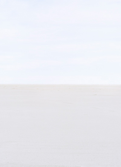 Minimalist composition divided horizontally into two tonal zones—a pale blue-gray upper section meeting a lighter beige-white lower section at a subtle horizon line. The soft, monochromatic palette and gentle gradations create a serene, atmospheric landscape.
