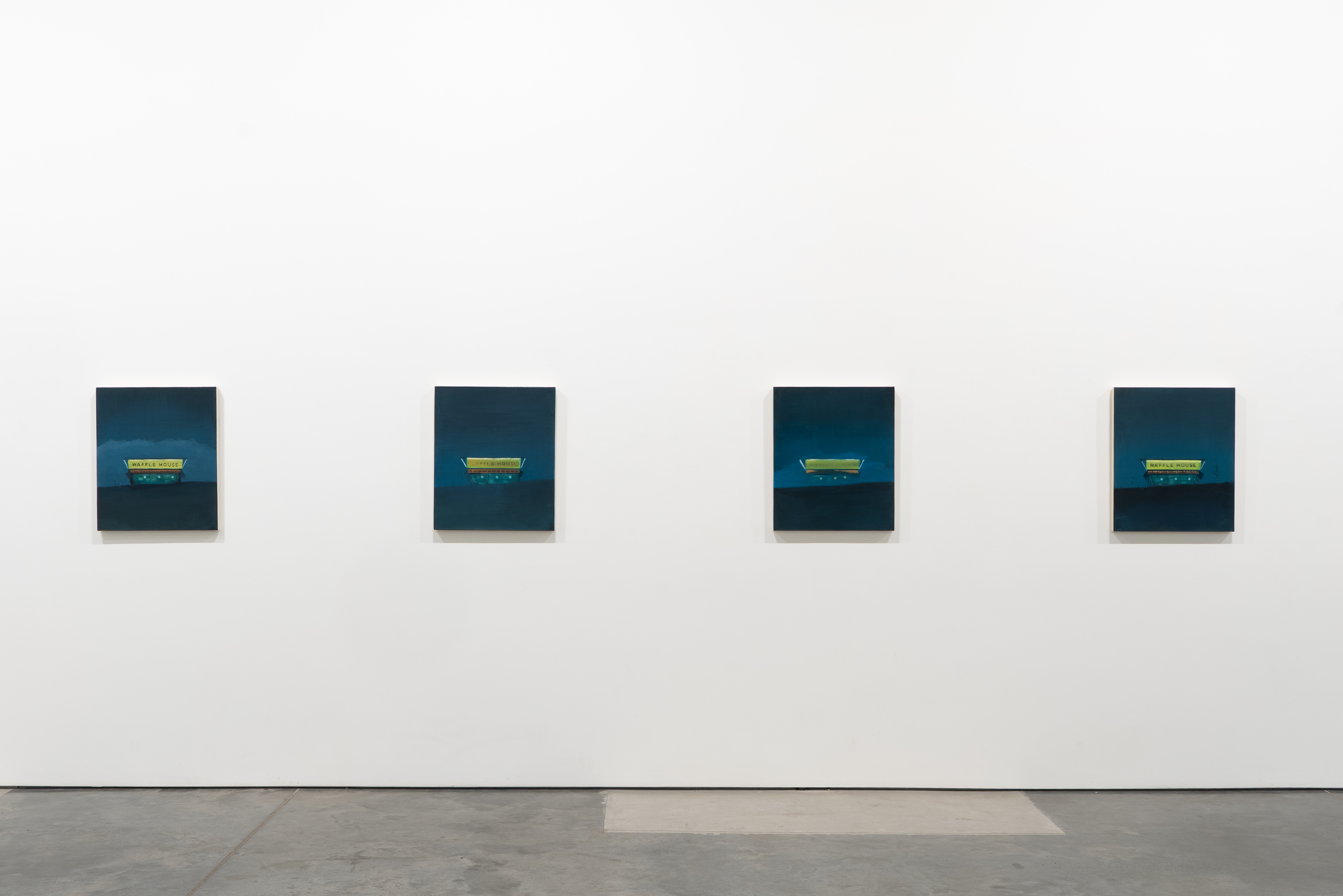 Four square paintings arranged horizontally on a white gallery wall, each depicting a glowing yellow-green diner or structure set against a dark teal sky and black landscape. The compositions are nearly identical, with subtle variations in the positioning and intensity of the illuminated buildings.