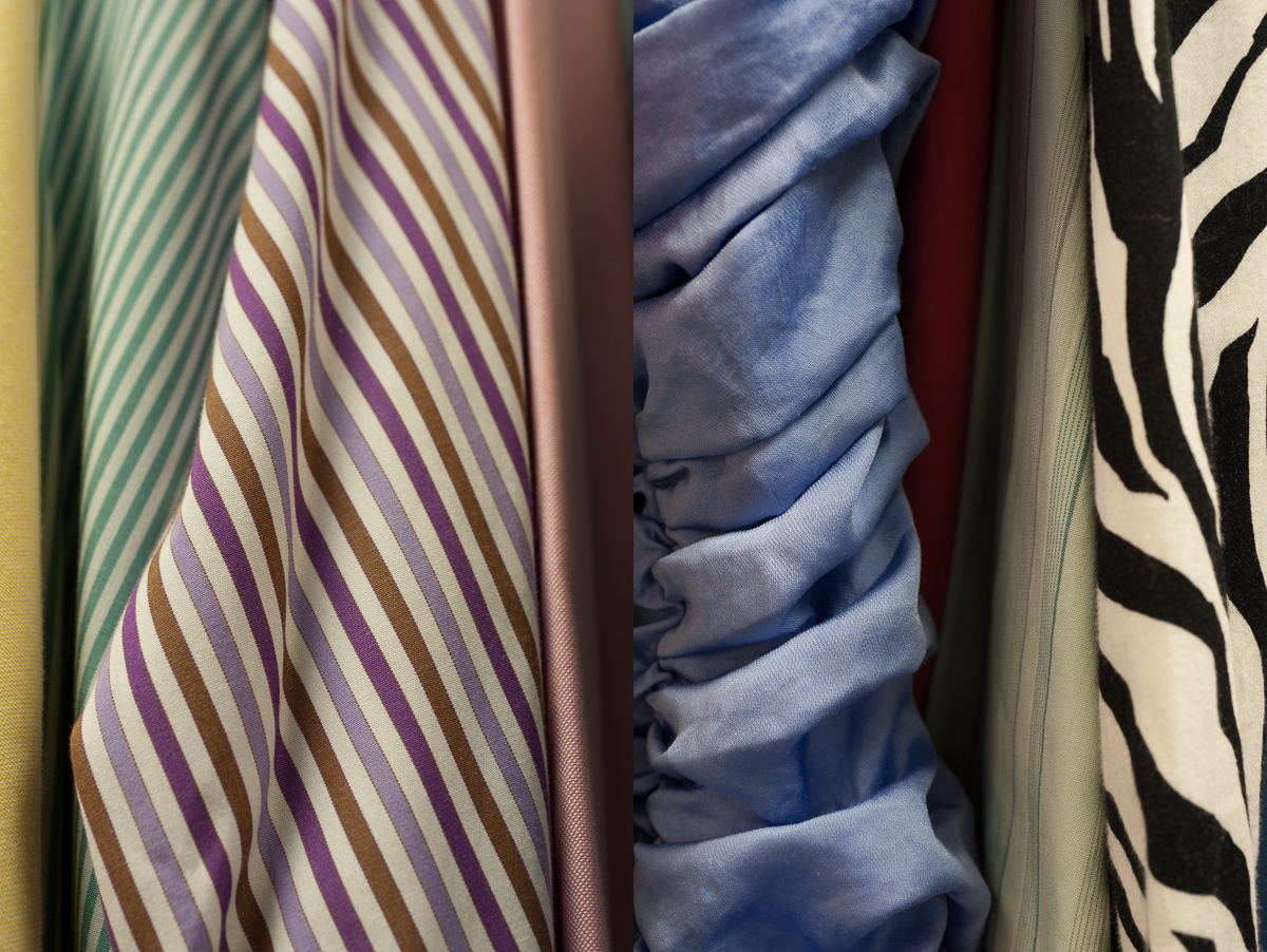 Close-up view of draped fabric samples displaying varied patterns: striped designs in purple, brown, and cream tones; solid-colored textiles in blue and burgundy; and bold zebra-stripe patterns in black and cream. The fabrics are arranged vertically with natural folds and shadows emphasizing their texture and dimensional quality.