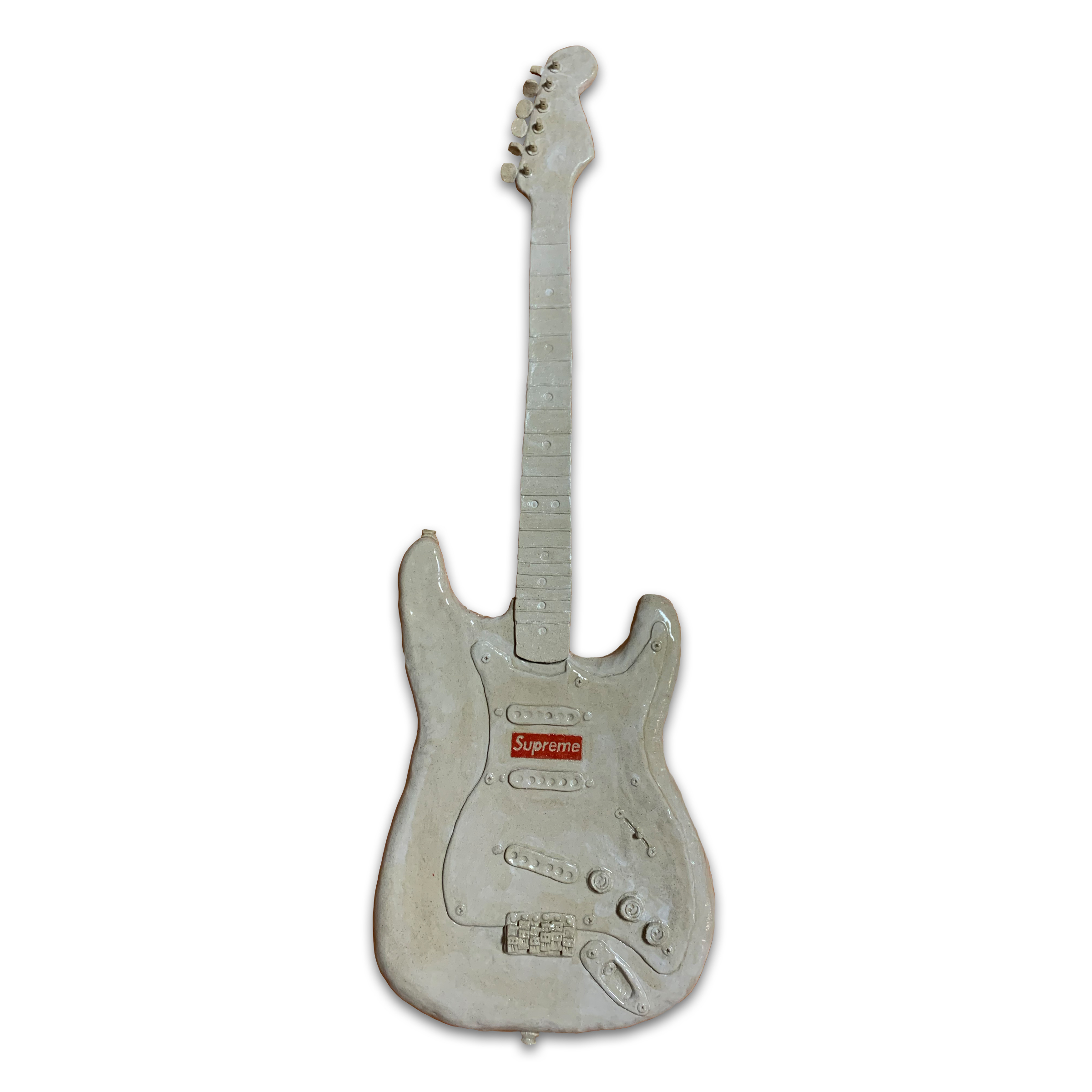 A ceramic electric guitar rendered in pale gray and white glazed clay, featuring a sculpted body with three pickup coils, control knobs, and a bridge, topped with a detailed neck and headstock. The guitar bears a small red rectangular label on its body and displays subtle surface variations suggesting hand-finishing and firing.