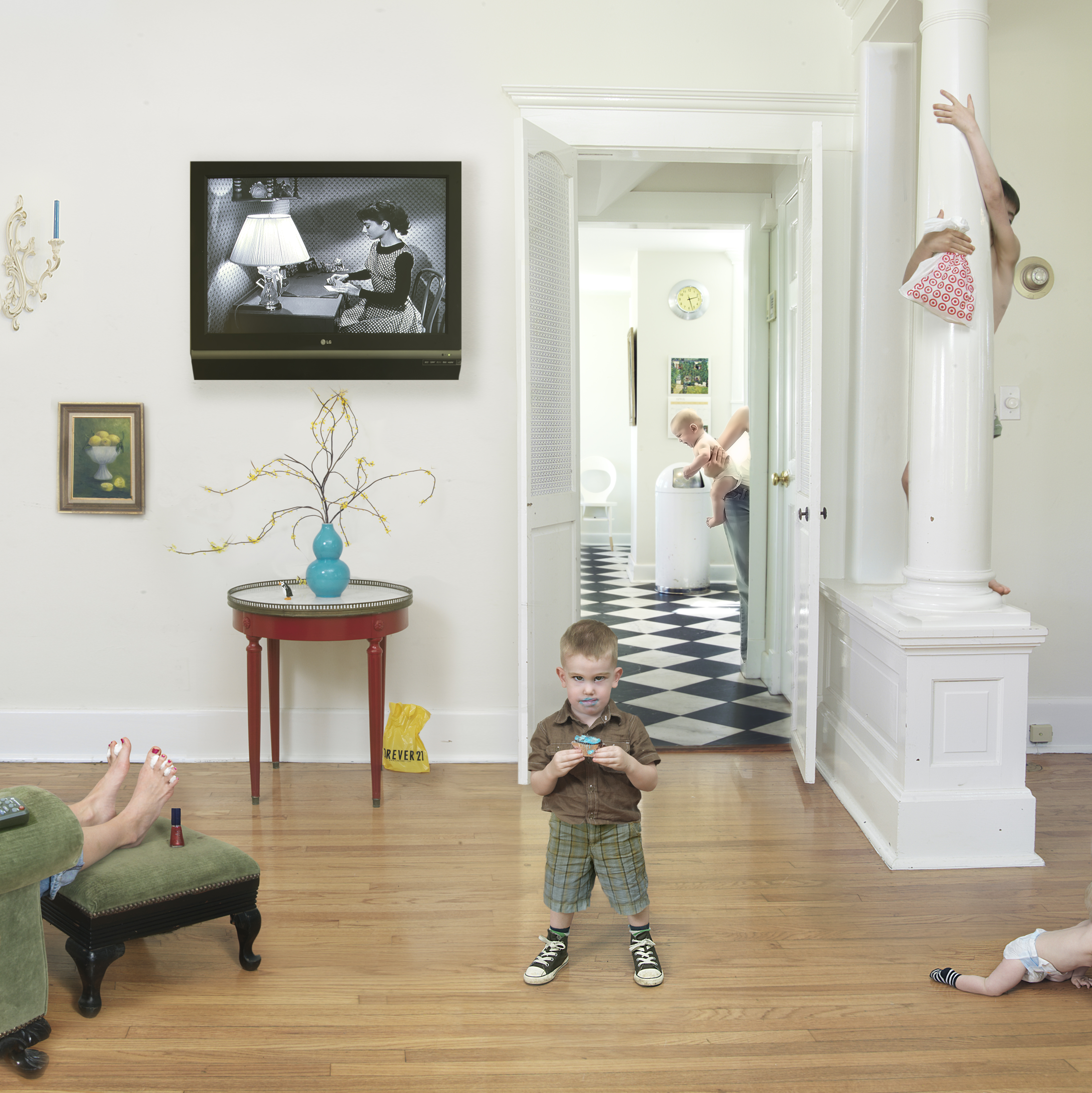 A domestic interior scene depicting children at play in a living room and adjoining hallway. The composition captures multiple figures in various poses—a child sitting on the floor in the foreground wearing brown and plaid shorts, another visible through an open doorway, and a third child on a white pedestal to the right with arms raised. The scene includes period furnishings: a red side table with turquoise vase, green upholstered chair, and television mounted on the wall displaying a black-and-white film. The space features light wood flooring, white walls, and a black-and-white checkered tile floor visible in the hallway, creating a layered perspective through multiple rooms.