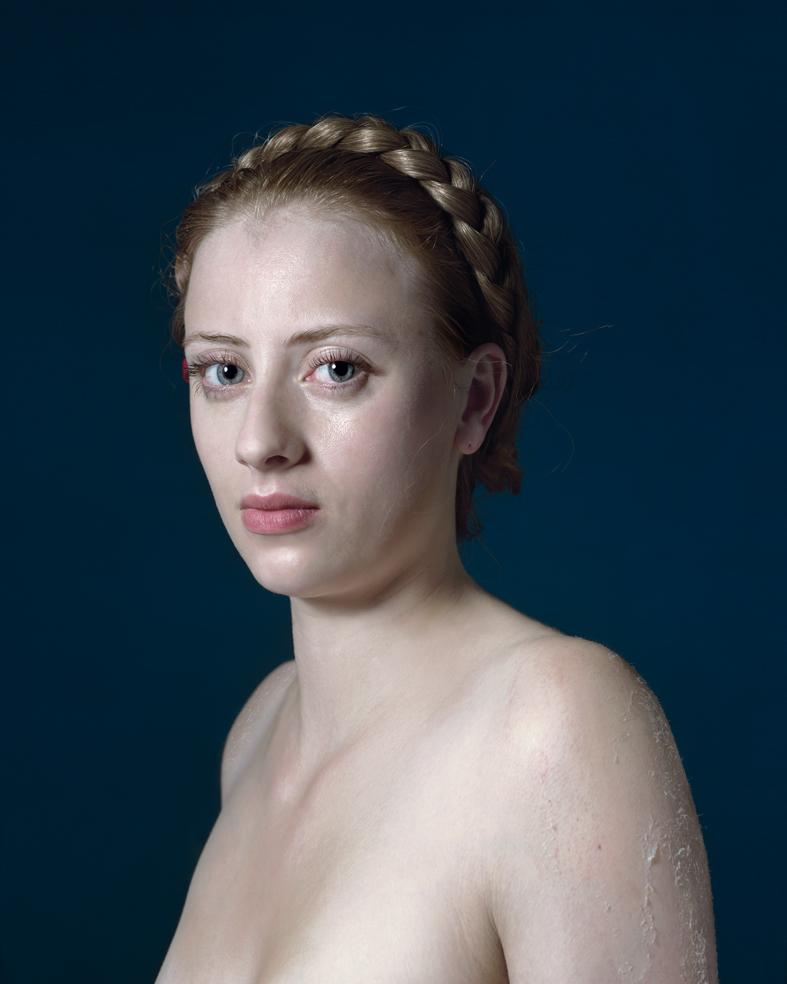 Portrait of a young woman with fair skin and braided hair styled close to her head, shown from the shoulders up against a deep teal background. She gazes toward the camera with a composed expression, her skin appearing wet or dewy, rendered in naturalistic detail with cool lighting that emphasizes the contrast between her pale complexion and the dark background.