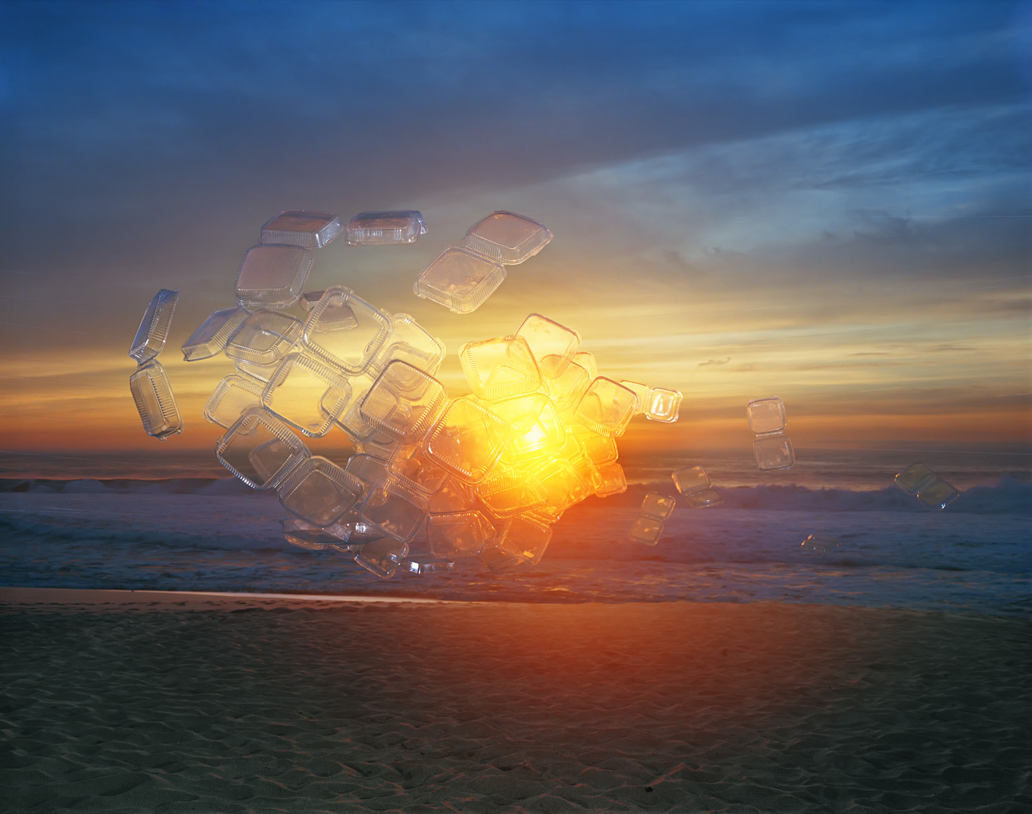 Translucent plastic takeout containers arranged in a glowing cluster emit a brilliant golden-yellow light against a dramatic sunset sky over a beach. The containers scatter across the sand, some closer and some distant, creating a surreal contrast between disposable materials and the natural seascape behind them.