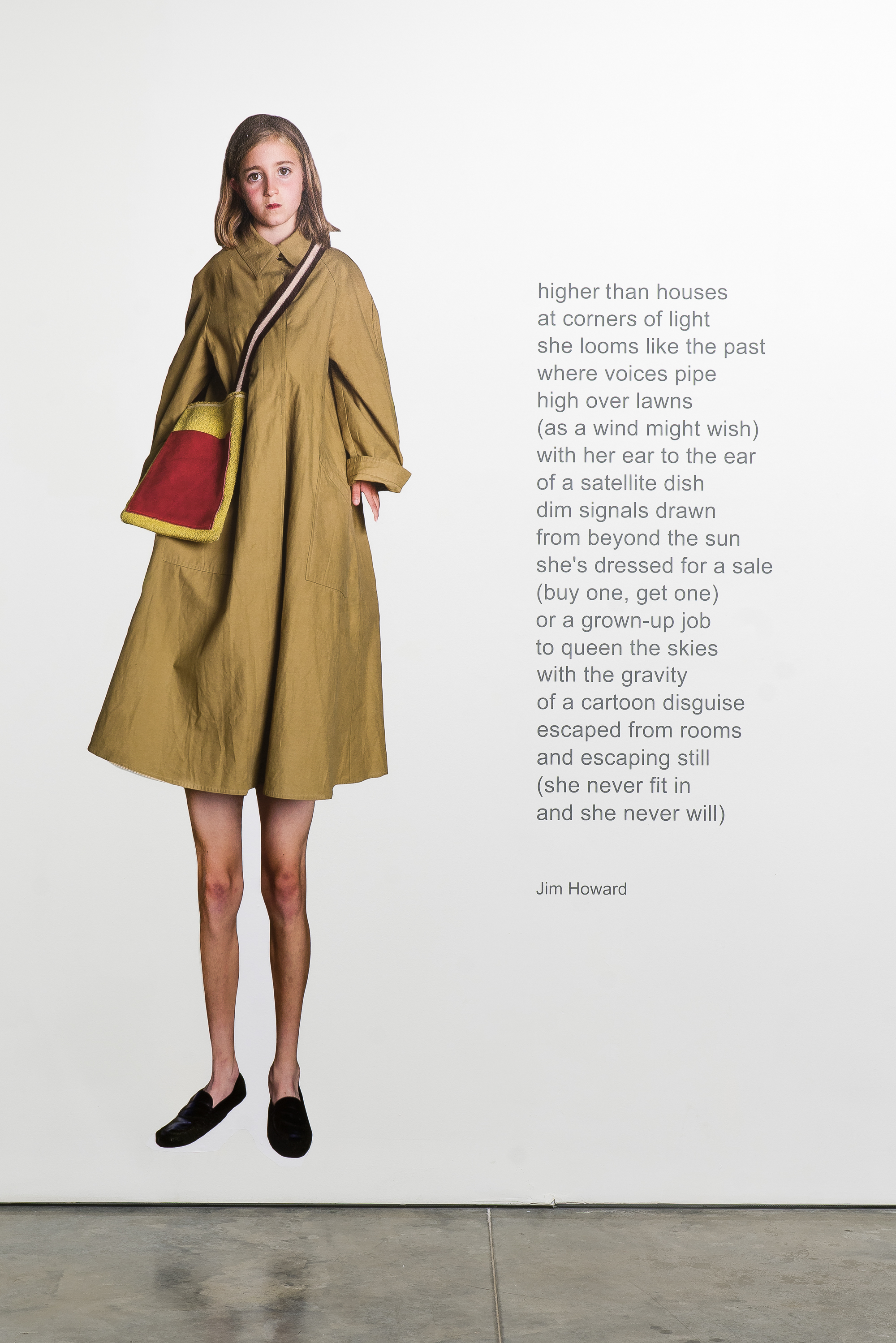 A young girl in a mustard-yellow coat with red and gold trim stands against a white background, wearing black slip-on shoes and carrying a red shoulder bag. Gray text overlays the right side of the image.