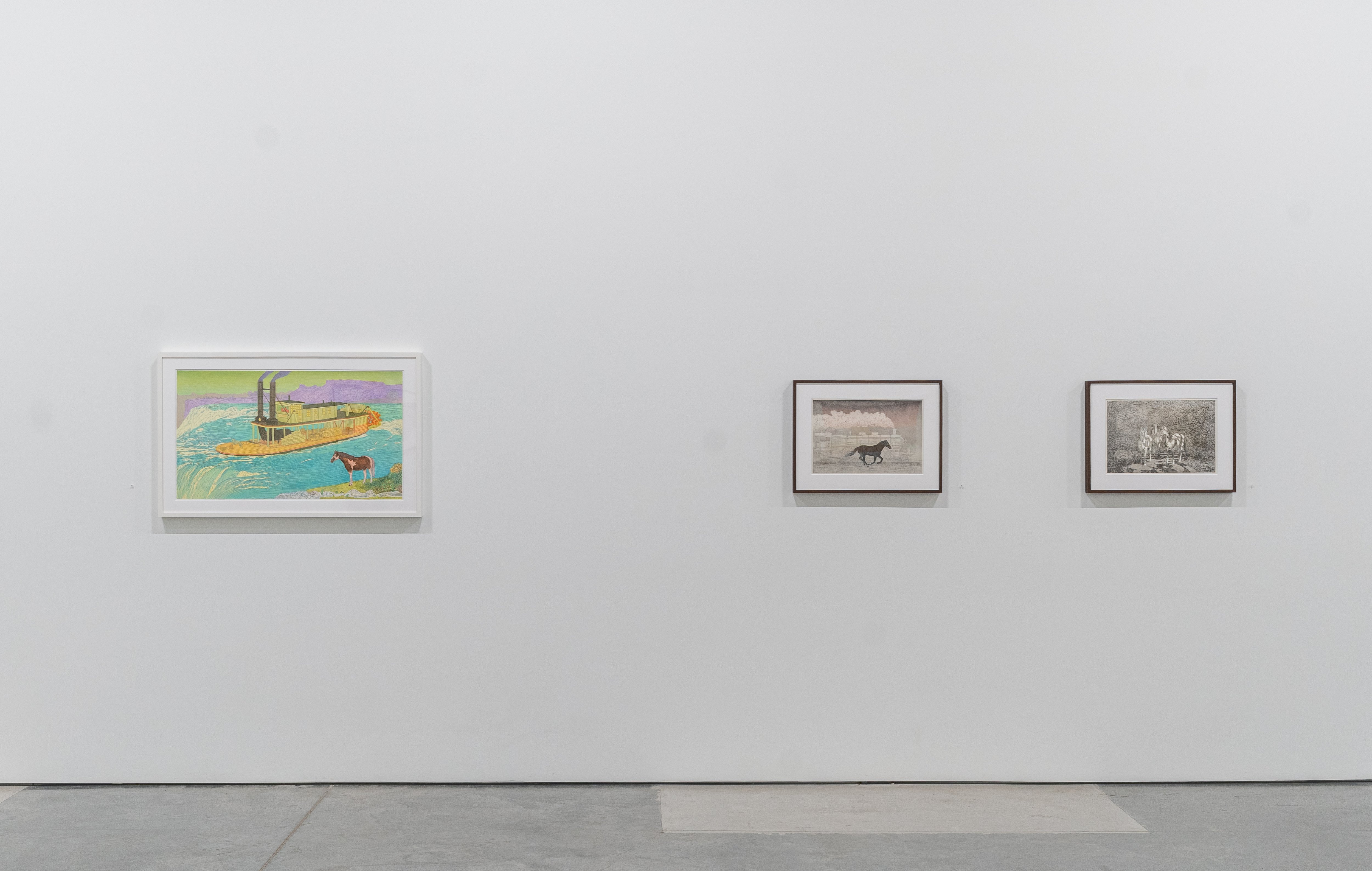 Gallery wall displaying three framed artworks: on the left, a colorful illustration in a white frame depicting a yellow boat with a red dog on turquoise water under a green and purple sky; on the right, two smaller grayscale framed prints, one showing a horse and the other showing a group of figures in a landscape.
