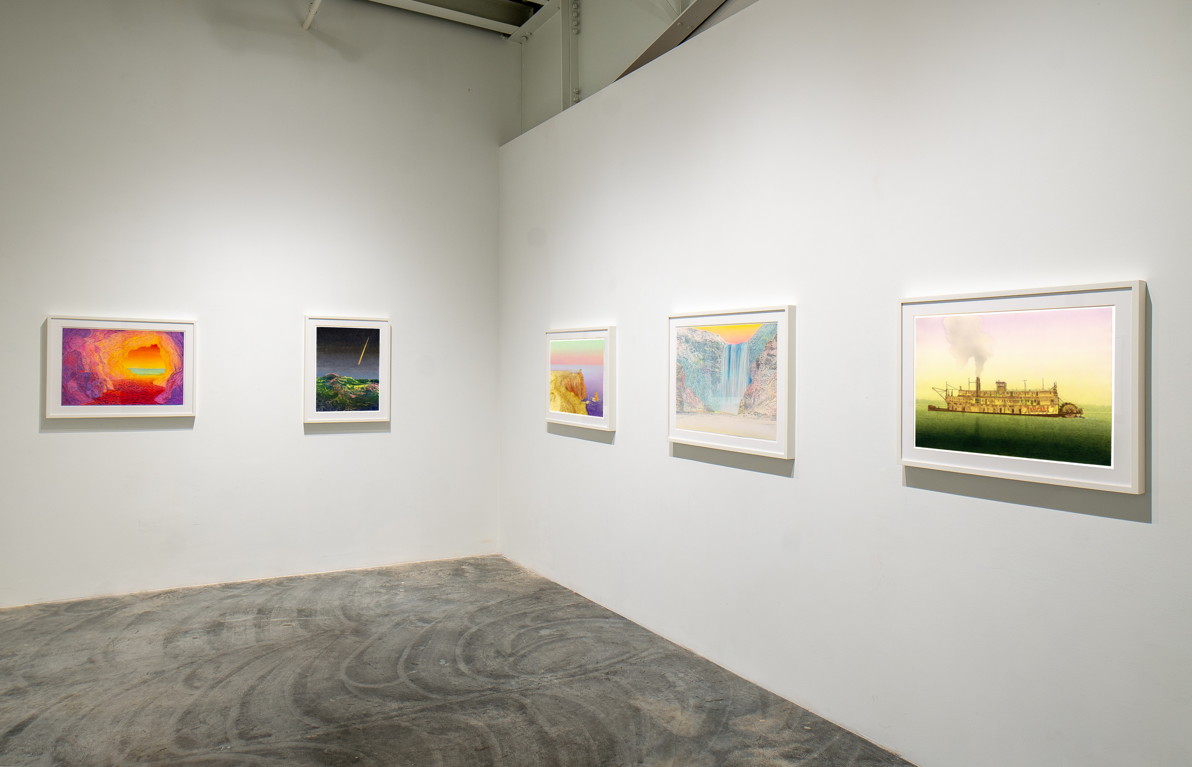 Five framed artworks hang on white gallery walls above a polished concrete floor. From left to right: a vibrant abstract composition in purples, oranges, and reds; a dark landscape with green terrain and stormy sky; a soft pastel sunrise or sunset; a ethereal waterfall cascading through layered blue and white tones; and a golden pastoral scene with a solitary structure in a verdant field. Each work is mounted in a light-colored frame with substantial matting.