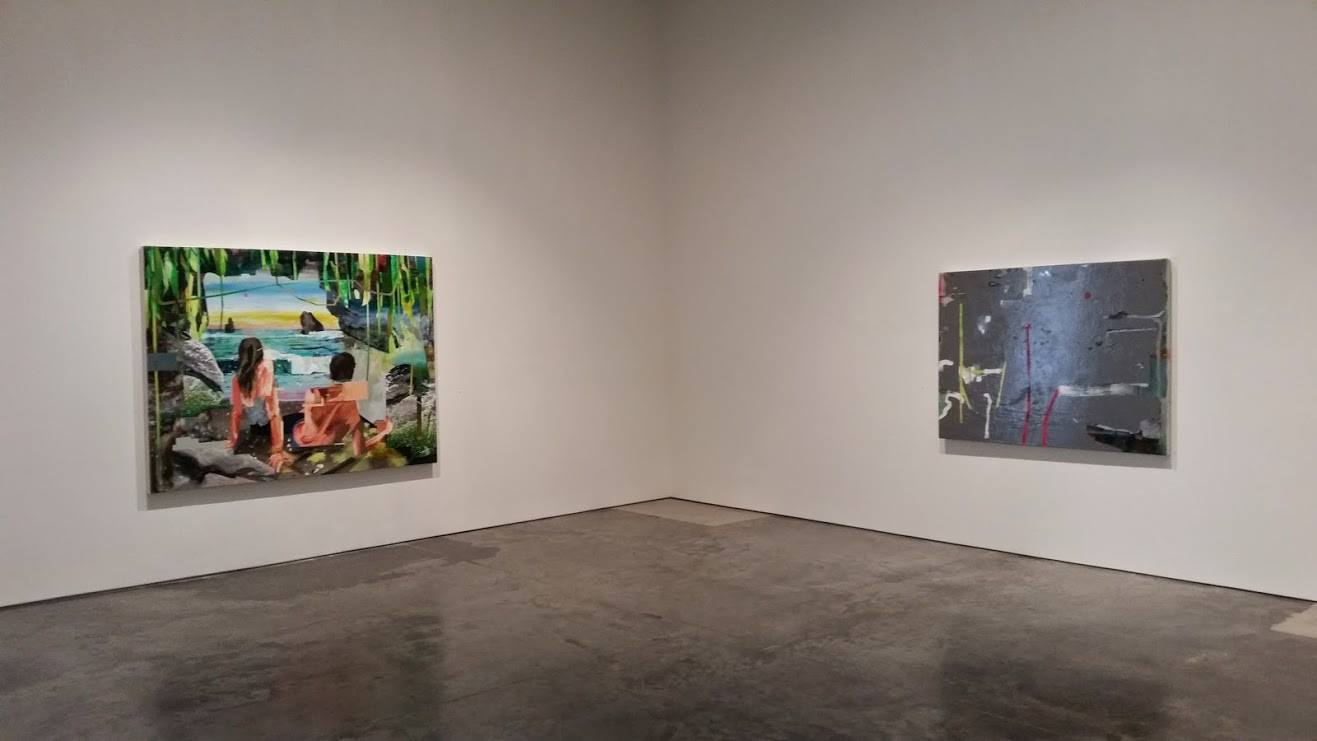 Gallery installation view featuring two framed artworks on white walls facing each other across a polished concrete floor. The left panel displays a colorful scene of figures in orange clothing seated by water with lush green vegetation, rendered in vibrant blues, greens, and earth tones. The right panel shows a darker, abstract composition with muted grays and blues featuring gestural marks and fragmented forms.