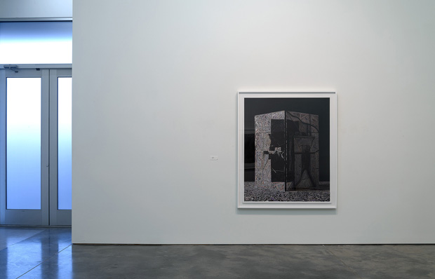 Black and white stippled drawing mounted in a silver frame on a white gallery wall, depicting an abstract architectural or geometric form with intricate dotwork creating depth and shadow against a dark background.